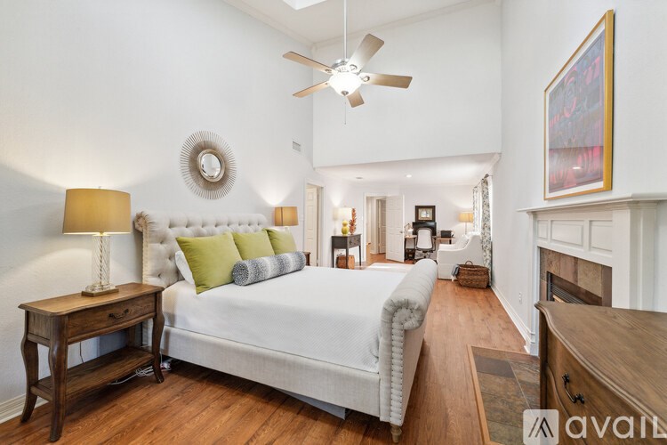 A bedroom with a large bed, a wooden nightstand, and a ceiling fan.