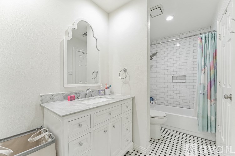 A white bathroom with a sink, mirror, and shower.