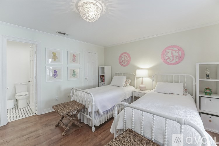 A bedroom with two beds, one with a white bedspread and the other with a white blanket.