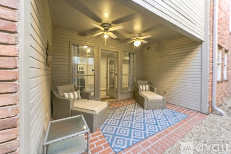 A covered porch with a ceiling fan and a bench.