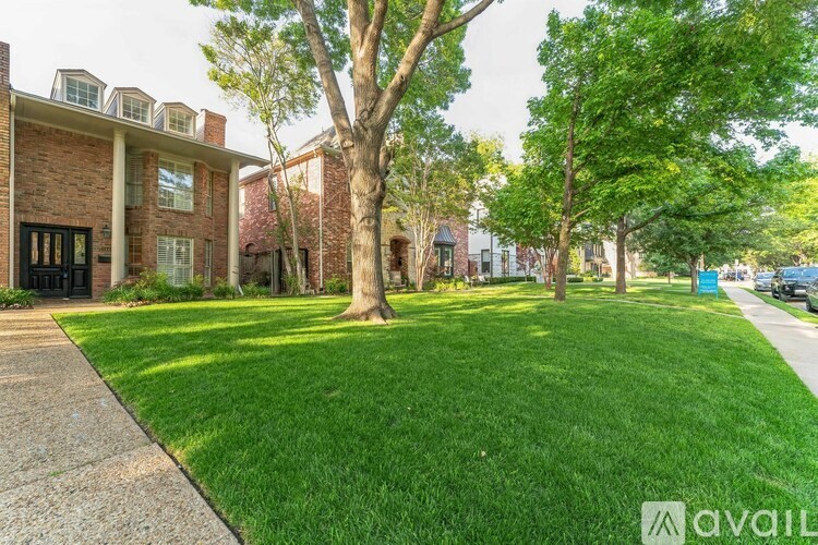 A well-maintained lawn in front of a brick house with a sidewalk.