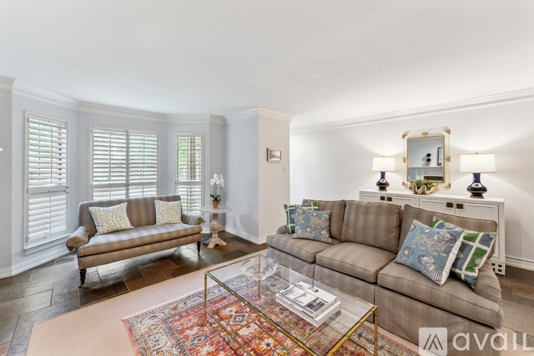 A living room with a brown couch and a glass coffee table.