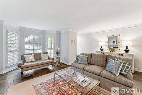 A living room with a brown couch and a glass coffee table.