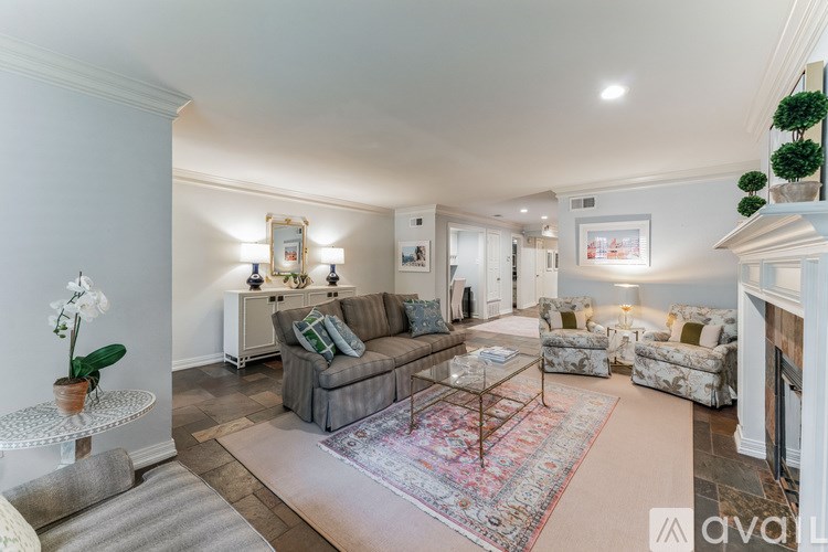 A living room with a grey couch and a red rug.