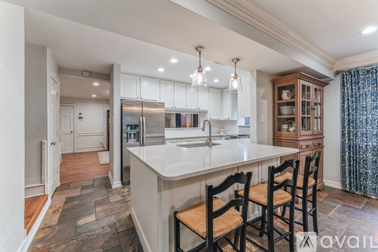 A kitchen with a large island and wooden chairs.