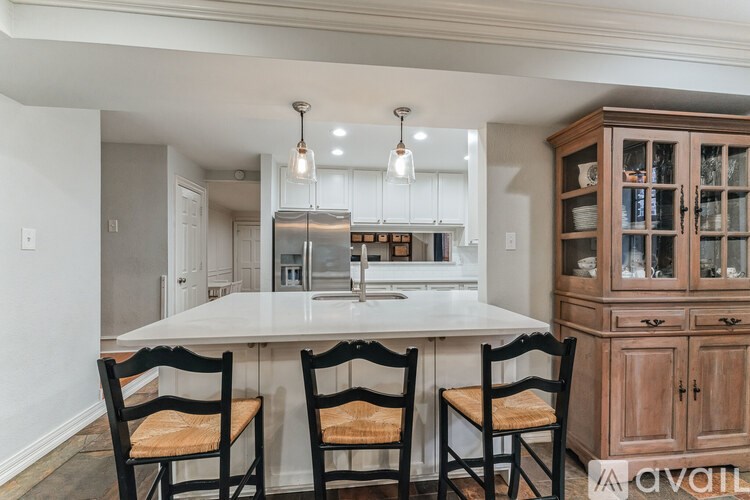 A kitchen with a white table and chairs with a wooden cabinet.
