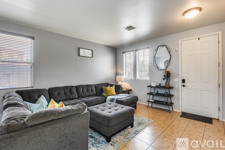 A living room with a grey sofa and a grey ottoman.