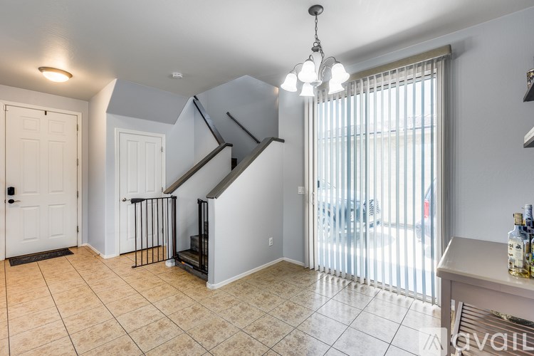 A living room with a staircase and a window with blinds.