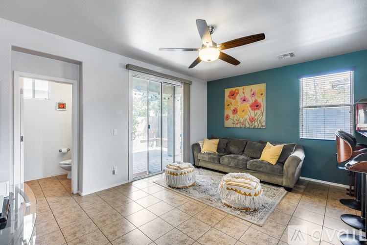 A living room with a couch, a rug, and a ceiling fan.