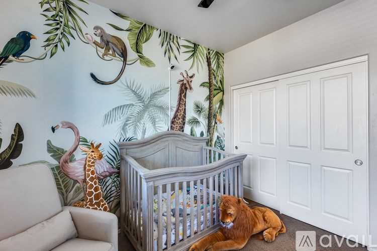 A baby room with a jungle wallpaper and a crib.