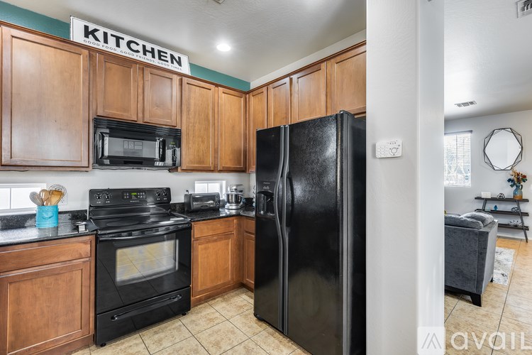 A kitchen with a black refrigerator and wooden cabinets.