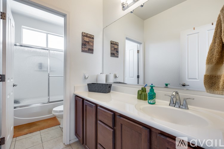 A bathroom with a white counter top and brown cabinets.