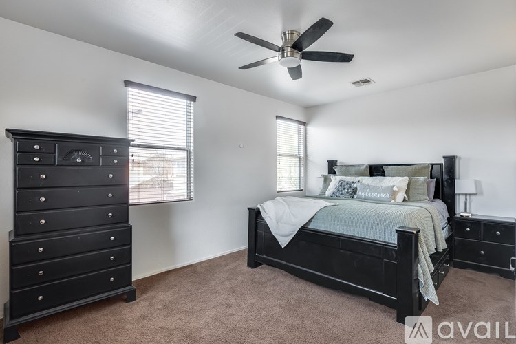 A bedroom with a large bed, a dresser, and a ceiling fan.