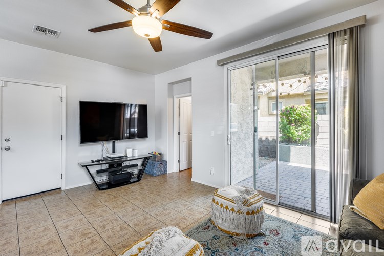 A living room with a flat screen TV and sliding glass doors.