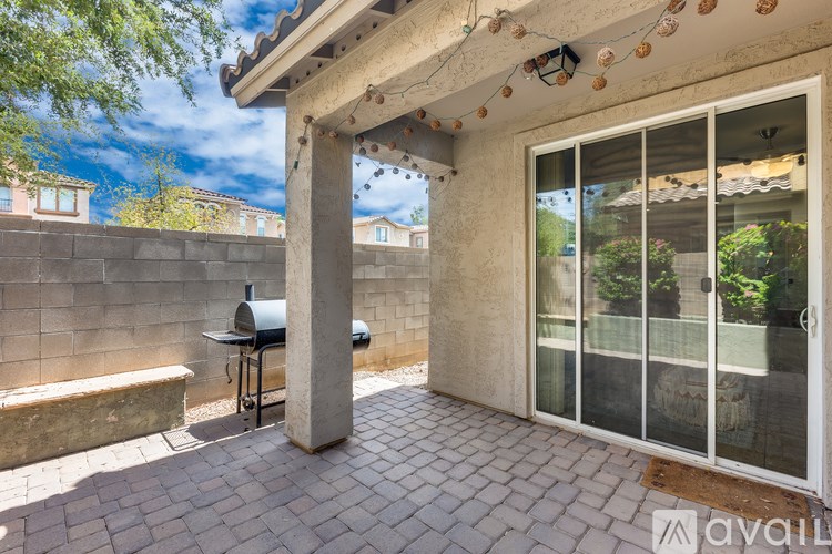 A patio with a table and chairs under a roof with decorative lights.