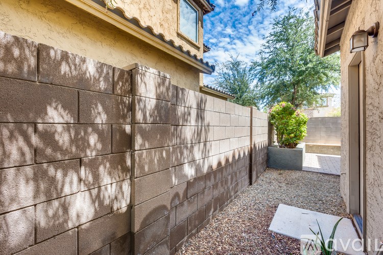 A wall of bricks with a tree in a pot in the background.