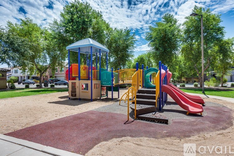 A playground with a red slide and a blue and yellow playhouse.