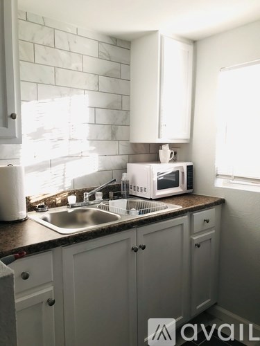 A kitchen with a sink, a microwave, and cabinets.
