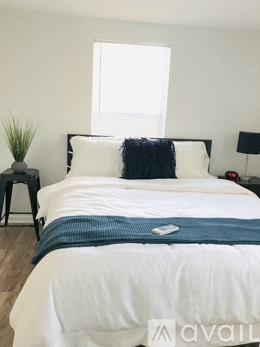 A bed with a white comforter and a blue throw.