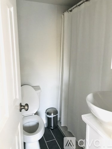 A white toilet sits next to a trash can in a small bathroom.