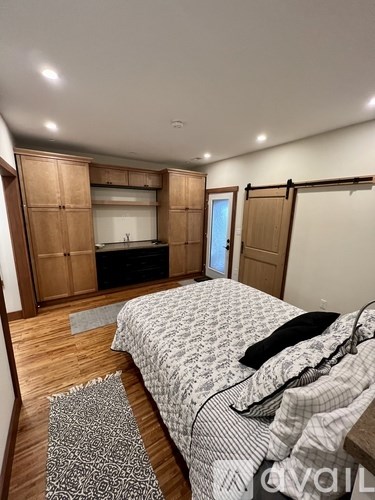 A bedroom with a bed, wooden floors, and a patterned rug.