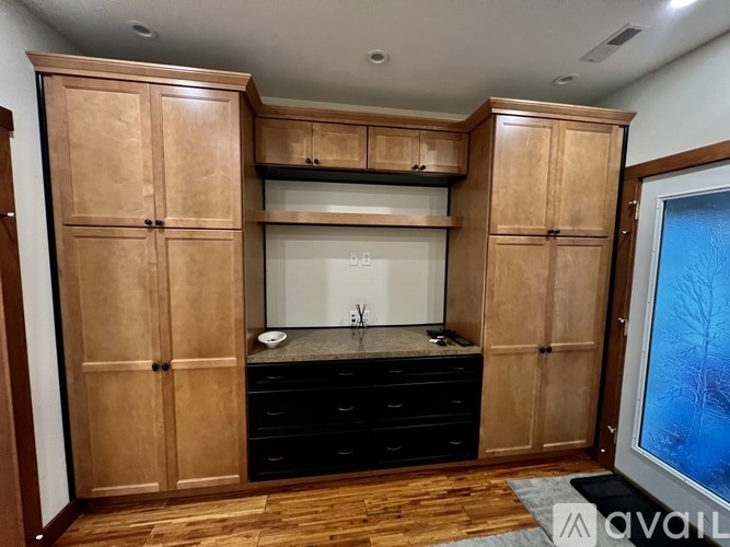 A kitchen with wooden cabinets and black drawers.