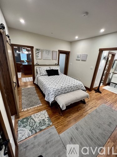 A bedroom with a bed, two rugs, and a wooden floor.