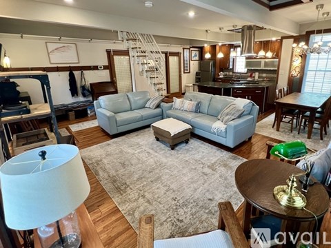 A living room with a grey rug and a white lamp.