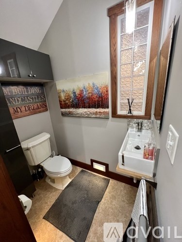 A bathroom with a toilet, sink, and a wall mural.