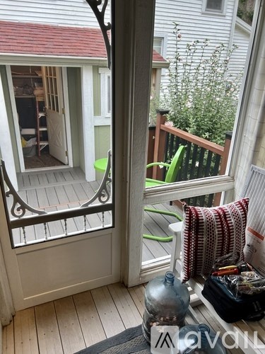 A balcony with a chair and a table with a bag on it.