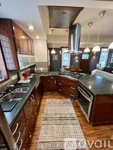 A kitchen with dark wood cabinets and a black counter top.