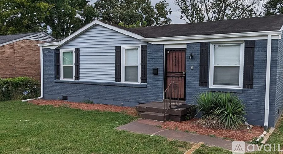 A blue house with a brown door and a red brick wall.