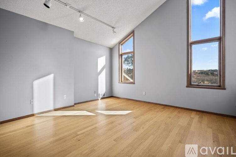 A spacious room with wooden floors and a large window overlooking the outdoors.