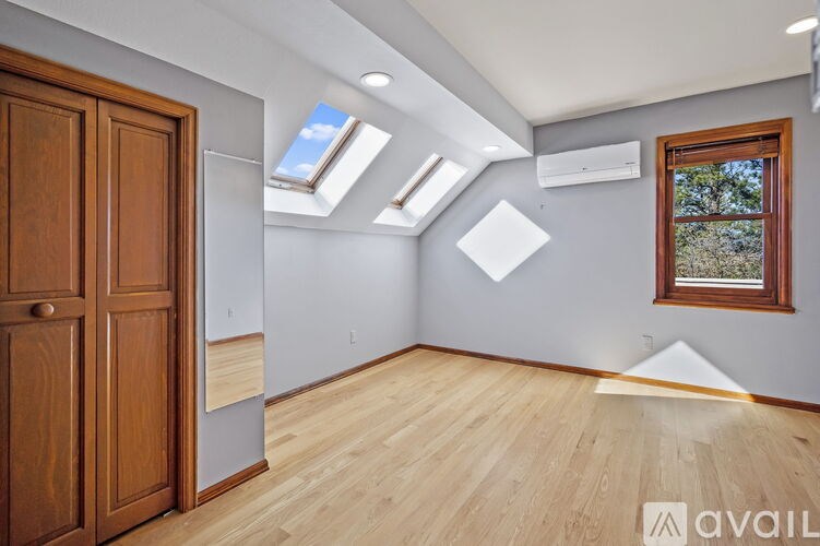A room with wooden floors and a window with skylights.