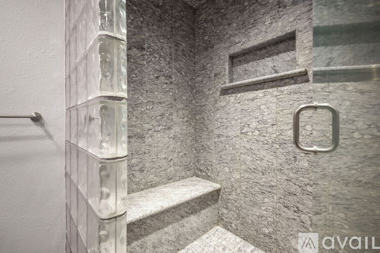 A shower area with a glass door and a metal handle.