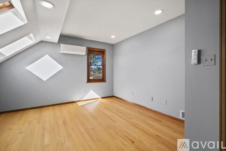 A room with wooden floors and a window with a view of trees.
