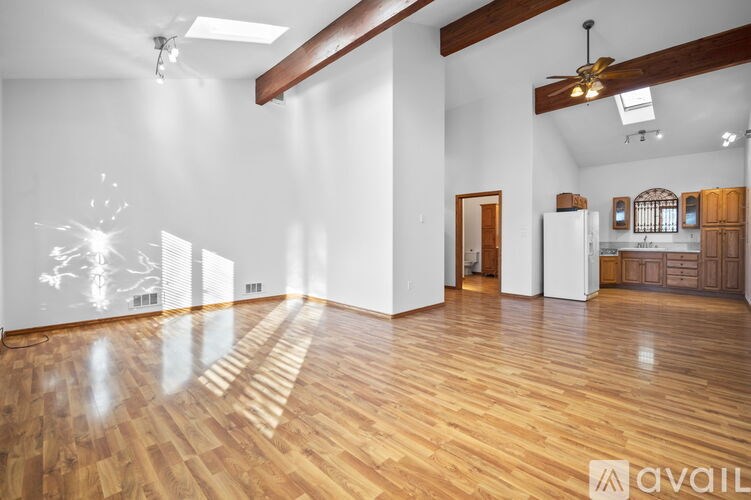 A spacious room with wooden floors and white walls.