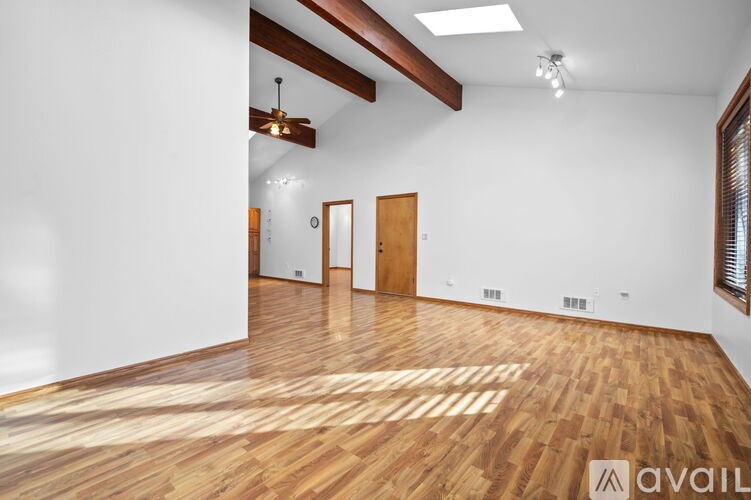 A spacious room with wooden flooring and white walls.