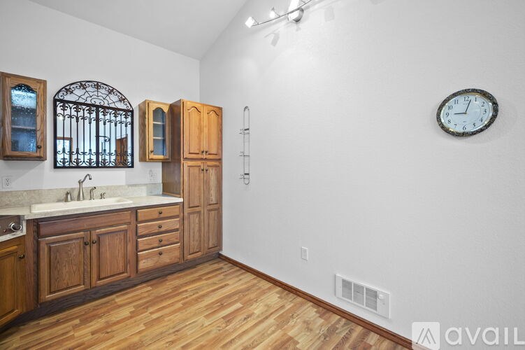 A kitchen with wooden cabinets and a clock on the wall.