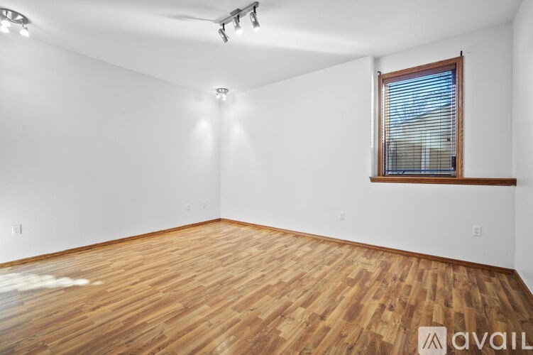 A room with wooden flooring and a window with blinds.