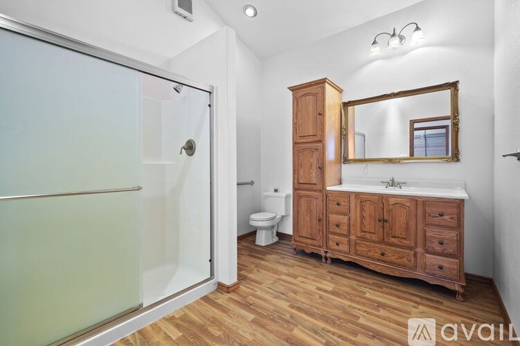 A bathroom with a wooden vanity and a walk-in shower.