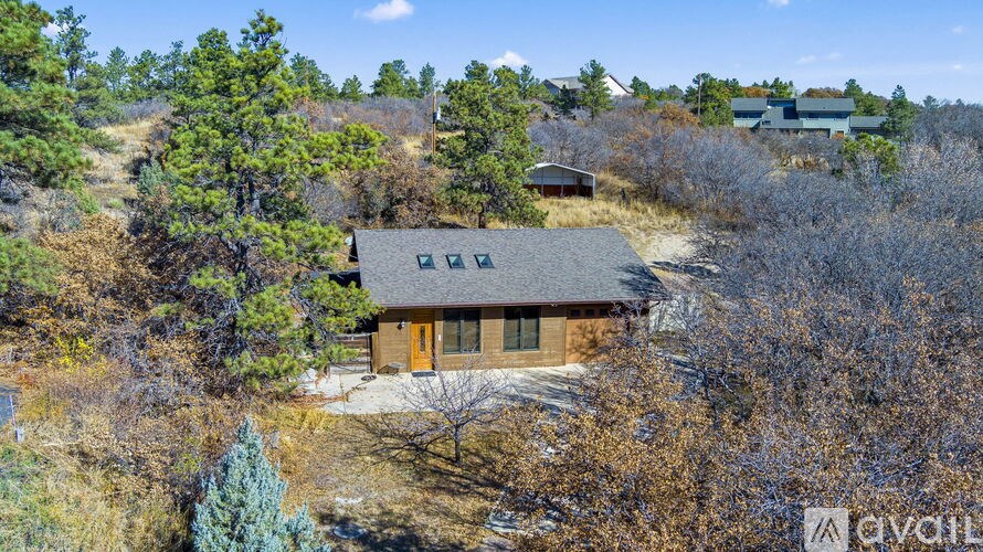 A house with a brown roof and a brown door is surrounded by trees.