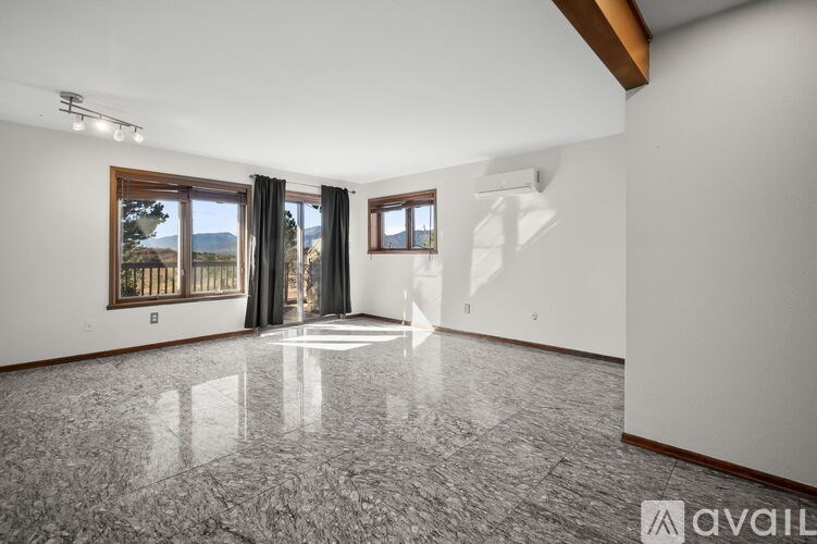 A spacious room with marble flooring and large windows.