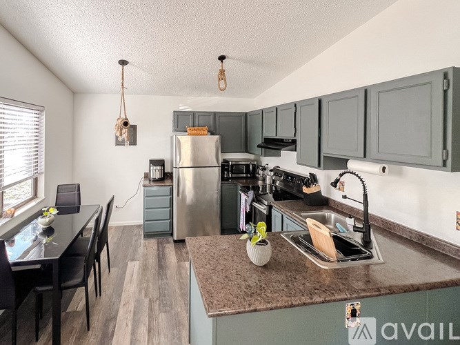 A kitchen with a refrigerator, sink, and cabinets.