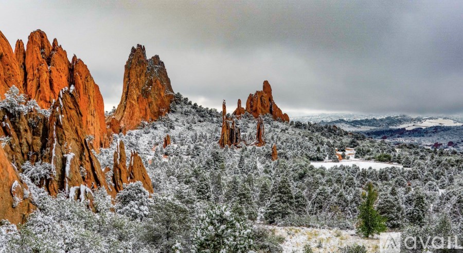 A landscape with red rock formations and snow-covered trees.