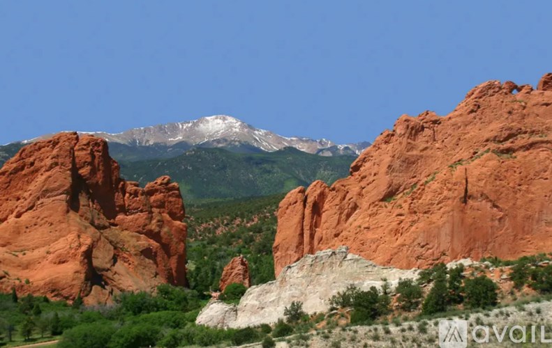 A mountain range covered in snow is in the background of a rocky landscape.