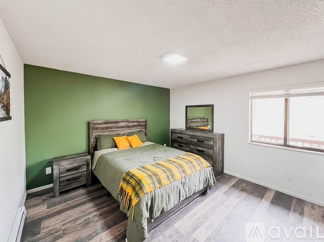 A bedroom with a bed, nightstand, and a window.