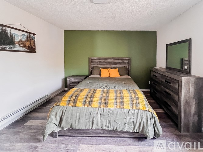 A bedroom with a bed, dresser, and a painting on the wall.