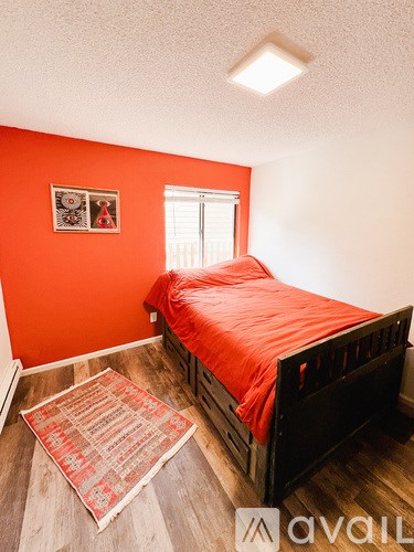 A bedroom with a bed and a rug on the floor.