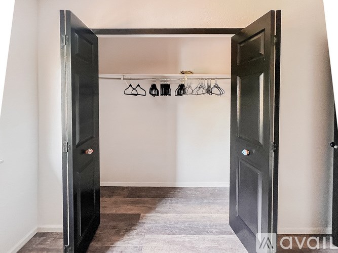A black door is open to a room with a pair of glasses hanging on a hook.